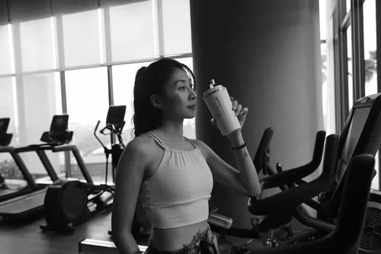 Woman drinking protein shake in gym after workout